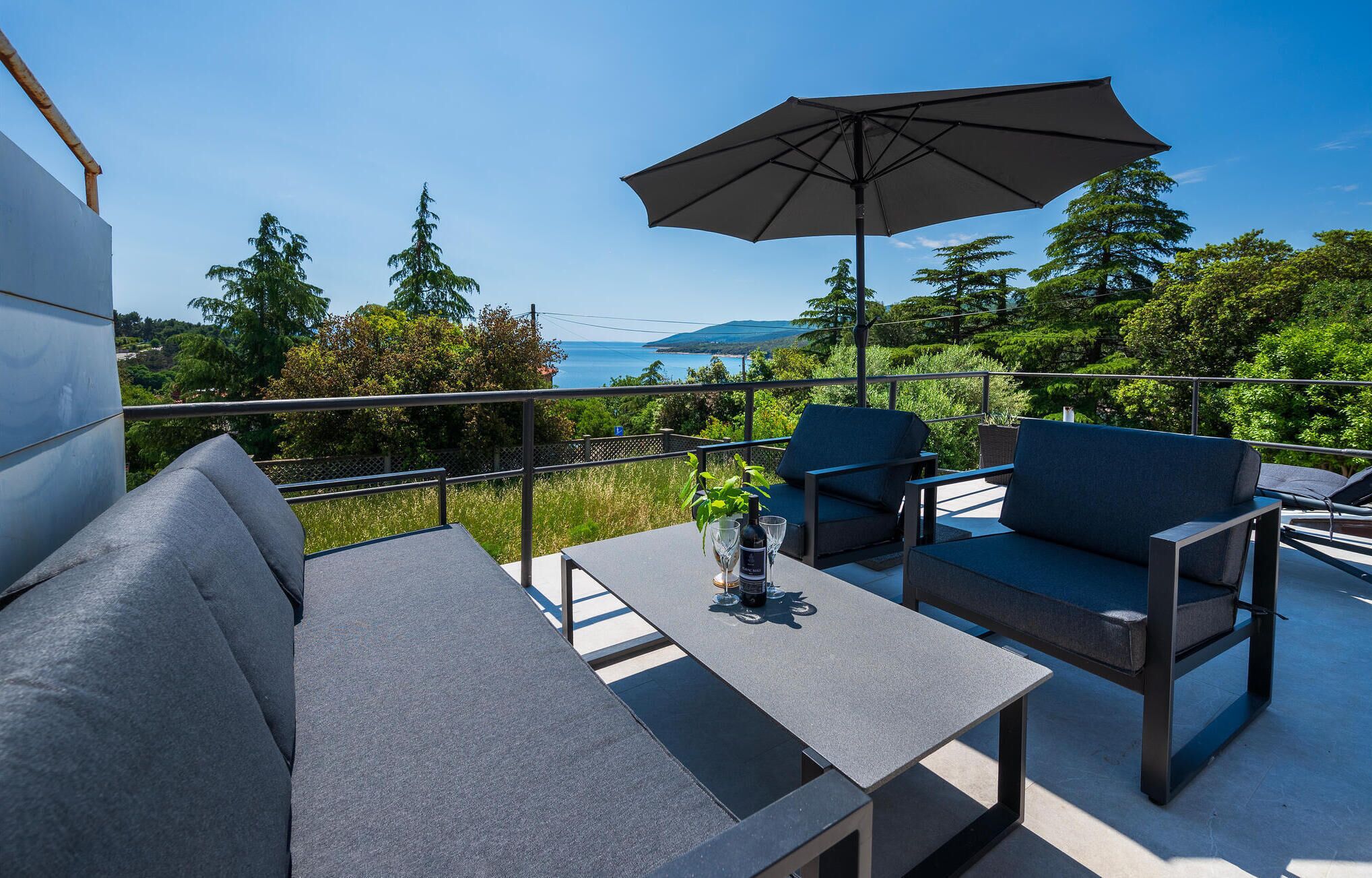 A balcony with outdoor seating, a table, and an umbrella.