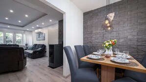 A modern dining area with a stone wall, a wooden table set with plates, glasses, and a vase of flowers.