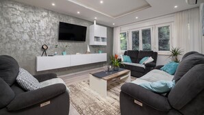 A modern living room with a grey sofa set, a coffee table, and a mounted TV.
