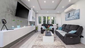 A modern living room with a grey sofa, a coffee table, and a TV mounted on the wall.