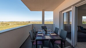 A balcony with a table set for two, chairs, and a view of a distant landscape.