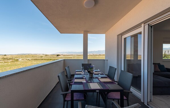Un balcón con una mesa para dos, sillas y vistas a un paisaje lejano.