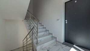 A staircase with marble steps and metal railings leading to a dark door.