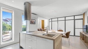 Eine moderne Küche mit Kochinsel, einem Essbereich mit Tisch und Stühlen sowie Blick ins Freie.