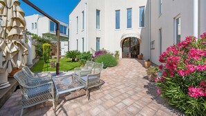 Ein Innenhof mit Terrassentisch und -stühlen, umgeben von Blumentöpfen und Blumen.