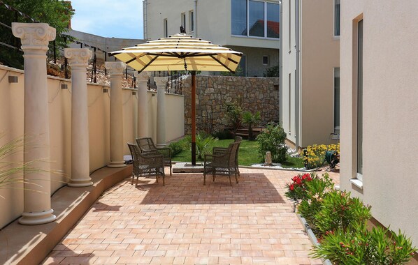 A patio with a table and chairs, an umbrella, and a stone wall.