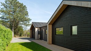 A modern wooden cabin with a sloped roof, a covered porch, and large windows.