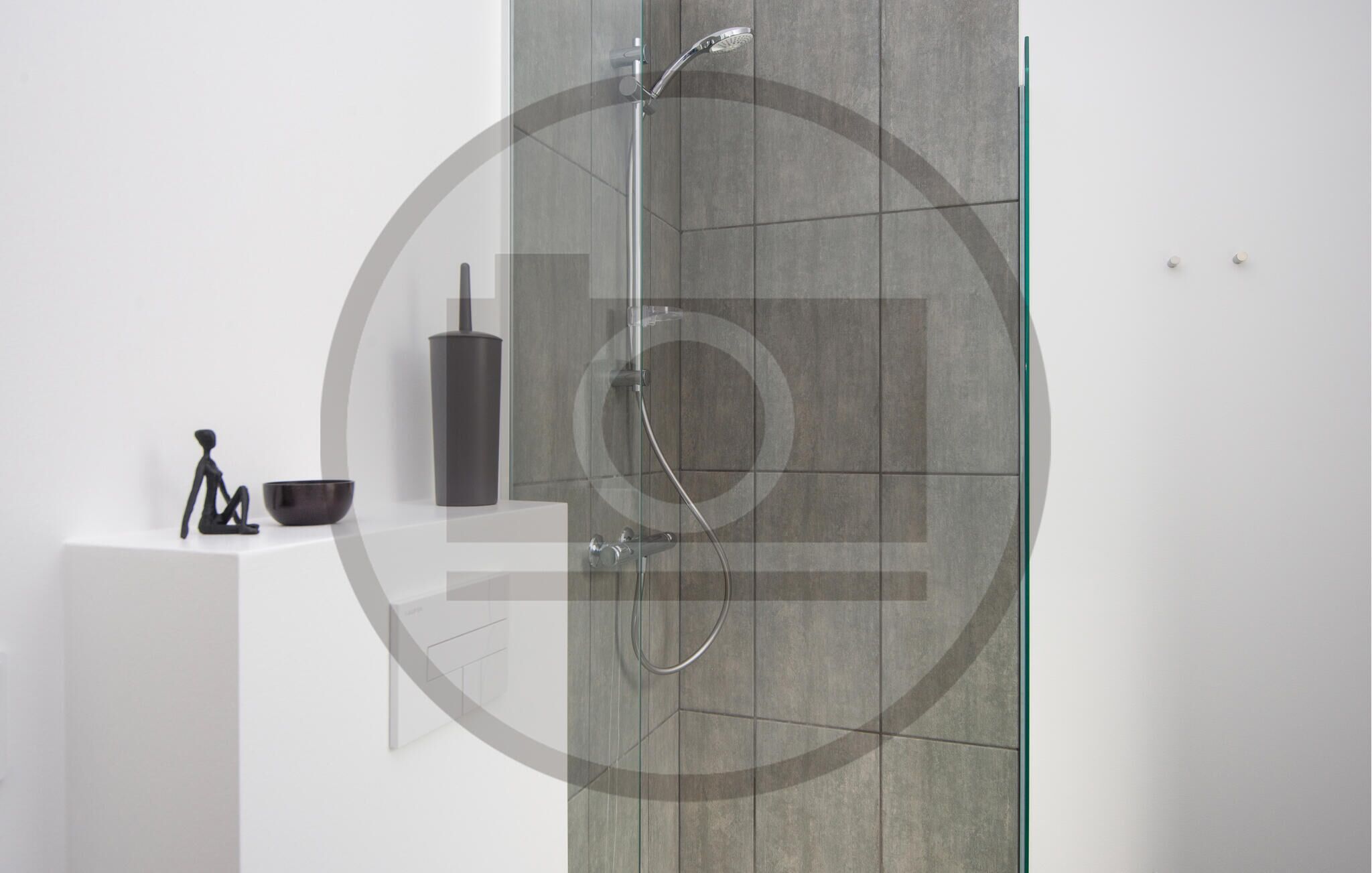Une salle de bain moderne dotée d’une douche à parois de verre, d’un distributeur de savon noir et d’un design minimaliste.
