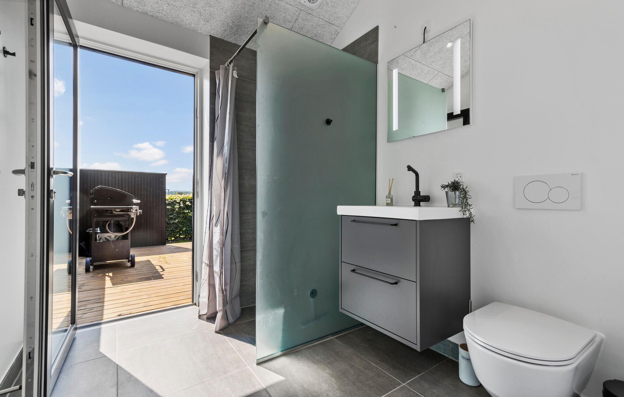 A modern bathroom with a shower, sink, and toilet.