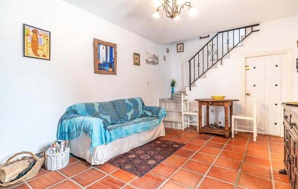 A living room with a sofa, a small table, a staircase, and a door. - Gorgeous home in Cómpeta - Málaga (Cómpeta - Málaga)