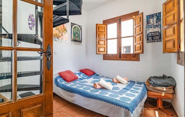 A bedroom with a bed, a wooden door, a window, and a wall with artwork. - Gorgeous home in Cómpeta - Málaga (Cómpeta - Málaga)