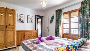 A bedroom with a bed, wooden wardrobe, and a door leading to another room. - Gorgeous home in Cómpeta - Málaga (Cómpeta - Málaga)