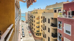 A narrow street flanked by multi-story buildings with balconies, a clear view of the sea, and parked cars. - Pet friendly apartment in Torrevieja with WiFi (Torrevieja)