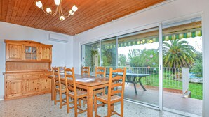 Un espace repas avec des meubles en bois, une porte vitrée donnant sur un patio extérieur et un plafond en bois.