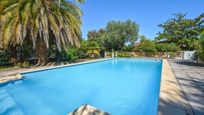 Une piscine rectangulaire à l’eau d’un bleu limpide, entourée d’une terrasse en pierre.