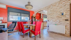 A dining area with a red and black color scheme, a chandelier, and a stone wall. - Pet friendly home in Segur de Calafell (Segur de Calafell)