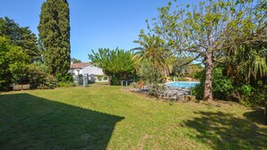 A backyard with a swimming pool, a tall tree, and a house in the background. - Awesome home in Moriani plage with outdoor swimming pool (Moriani plage)