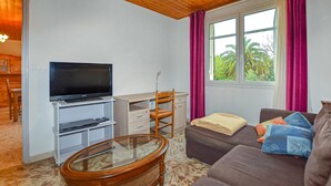 A compact living space with a television, a desk, a chair, a sofa, and a window with curtains. - Awesome home in Moriani plage with outdoor swimming pool (Moriani plage)