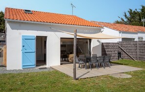 Uma casa com telhado de telhas, um pátio com mobiliário externo e um deck de madeira.