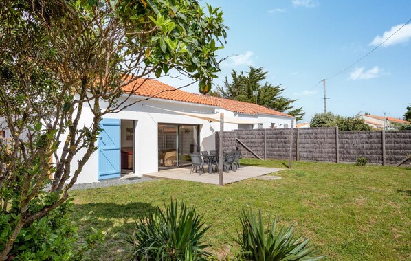 Uma casa moderna com telhado em cerâmica, quintal cercado e um alpendre com mobiliário de exterior.
