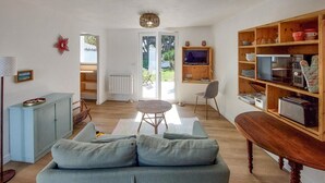 Un saló amb un sofà, una taula de dinar, una televisió i una biblioteca.
