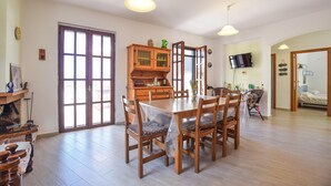 A dining area with a wooden table and chairs, a cabinet with glass doors, and a television mounted on the wall. - Amazing home in Perdifumo (Perdifumo)