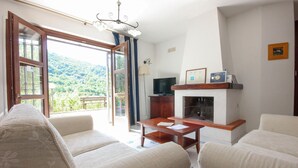 A living room with a sofa, a coffee table, a fireplace, a television, and a view of a mountainous landscape through a large window. - 5 bedroom beautiful home in Sessa Cilento (Sessa Cilento)