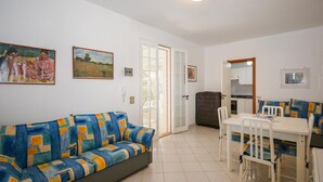 Ein Wohnzimmer mit einer Couch, einem Esstisch mit Stühlen und einem durchgehenden Durchgang zur Küche.