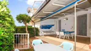 Eine überdachte Terrasse mit Tisch, Stühlen, einer Schaukel und einem Tor.