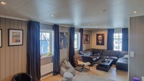 Een moderne woonkamer met een bruine leren bank, een geruit fauteuil, een klein tafeltje en een grijze kruikzak.