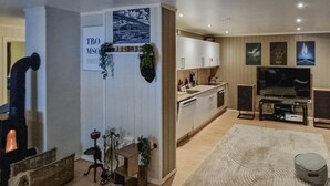 Een moderne keuken met witte kasten, een inbouwoven en een grote flatscreen televisie.