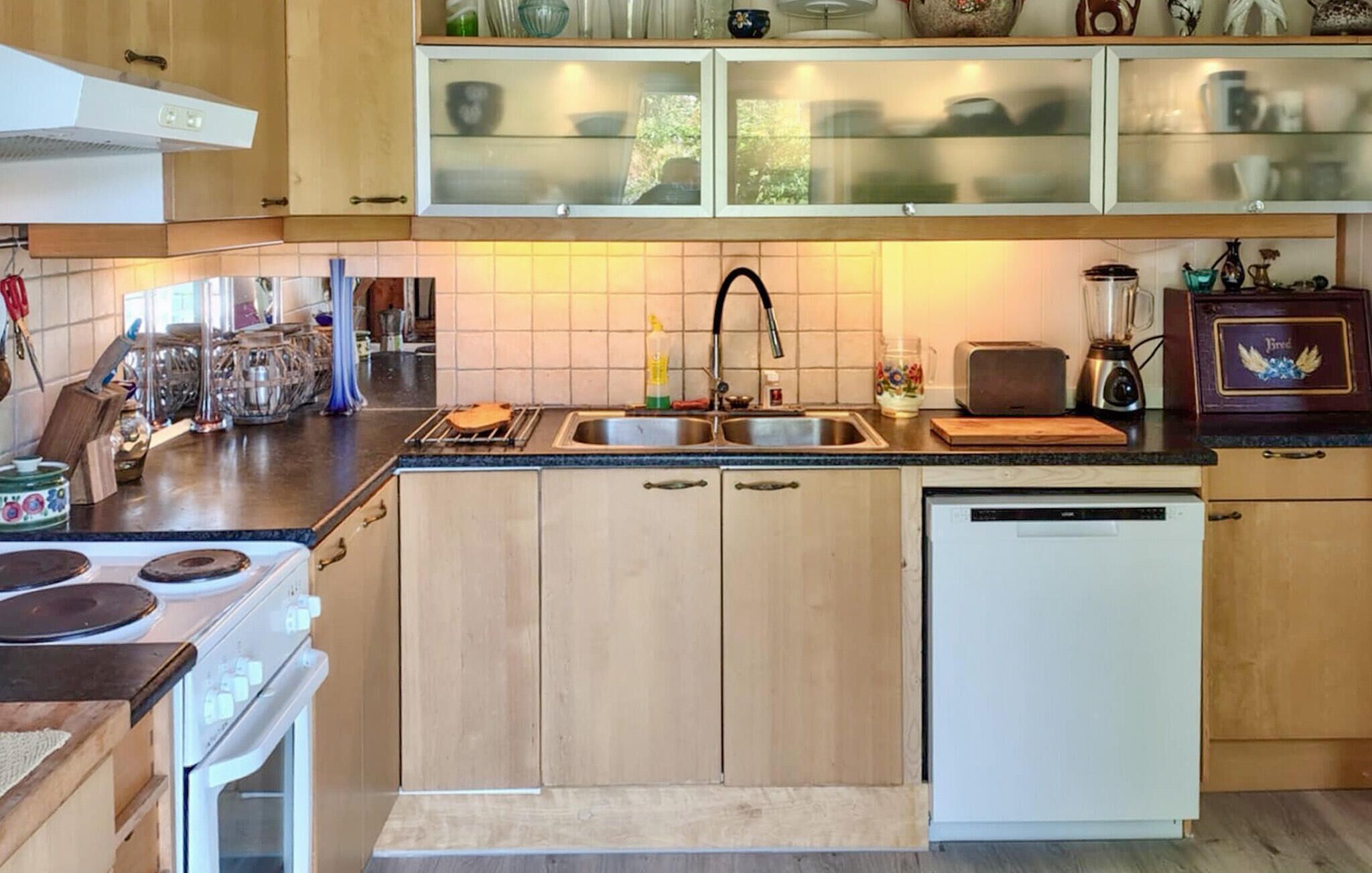 A kitchen with wooden cabinets, a double sink, a stove, and a dishwasher.