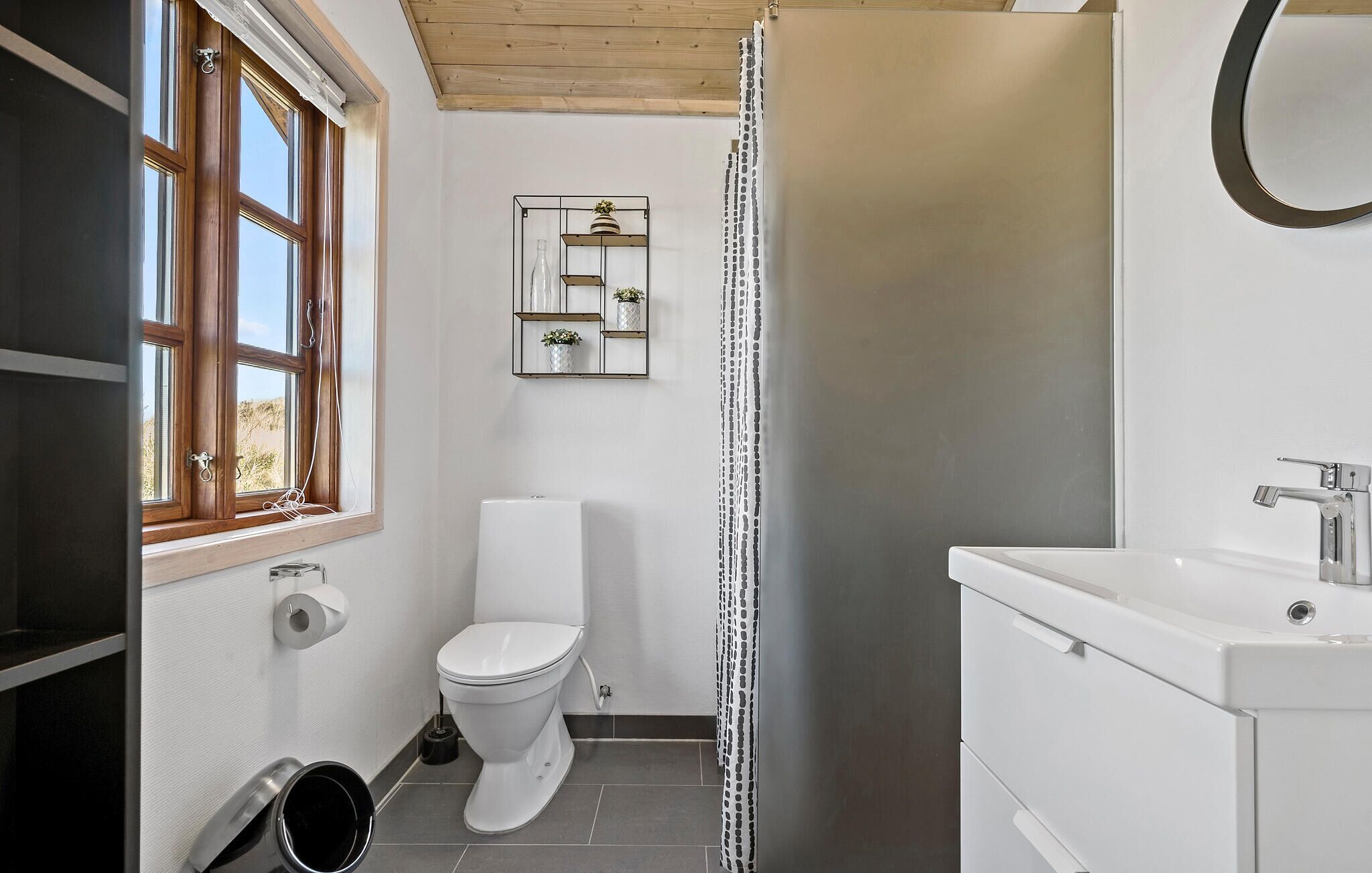 Een kleine badkamer met toilet, wastafel en raam.