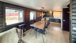 Una cocina moderna con una mesa y sillas de madera, horno empotrado y un ventanal con vista a un edificio rojo.