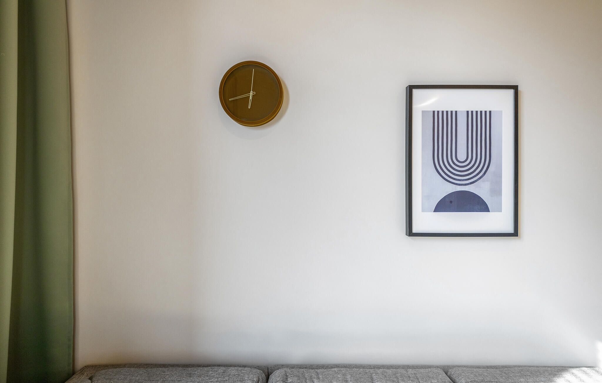 A wall with a round clock and a framed abstract artwork.