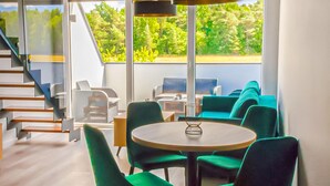 A modern interior with a staircase, green seating, and a view of greenery outside. - Beautiful apartment in Nowecin with sauna (Nowecin)