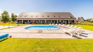 A modern building with a swimming pool, lounge chairs, and a covered patio area. - Cozy apartment in Nowecin with sauna (Nowecin)
