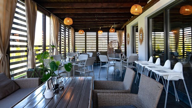 A restaurant with outdoor seating, wicker furniture, and hanging pendant lights. - Cozy apartment in Nowecin with sauna (Nowecin)