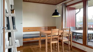 Ein gemütliches Zimmer mit einer hölzernen Sitzbank, einem Tisch und Stühlen. Ein großes Fenster bietet einen Blick nach draußen.
