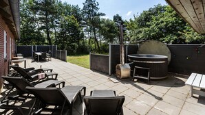 Un patio al aire libre con una parrilla, zona de estar y un jacuzzi.
