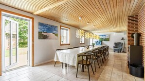 Un comedor espacioso con una mesa larga, sillas y techo de madera.