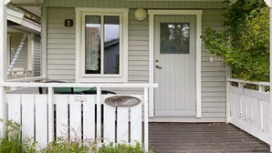 Una casa con porche, una puerta y un letrero pequeño.
