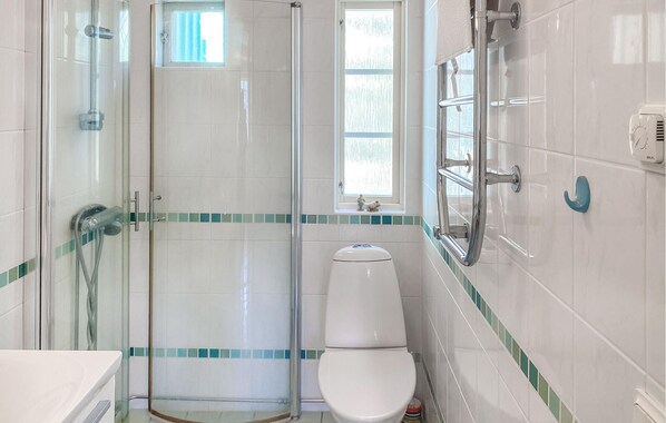 A bathroom with a glass-enclosed shower, a toilet, and a sink.