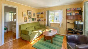 Un salón acogedor con un sofá verde, una mesa de centro redonda, un sillón de cuero y una estantería llena de libros.