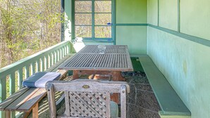 Una mesa de picnic de madera con bancos, un banco con respaldo y una ventana que da a las árboles.