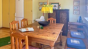 Comedor con una mesa de madera, sillas, un cuenco negro y una mesita con mantel amarillo.