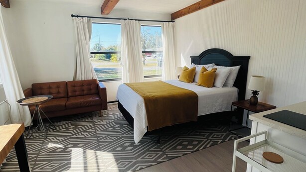 Ett hotellrum med en säng, en soffa, ett skrivbord och utsikt över omgivningarna.