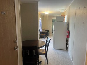A compact kitchen with a refrigerator, a dining table with chairs, and a water heater access sign on the door. - Charming 1-bedroom tiny house in awesome Chester with WiFi, central AC and Heat. (Chester)