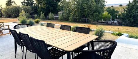 An outdoor patio with a rectangular wooden table and black wicker chairs.