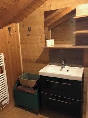 A wooden-paneled bathroom with a white sink, a mirror, and a towel rack.